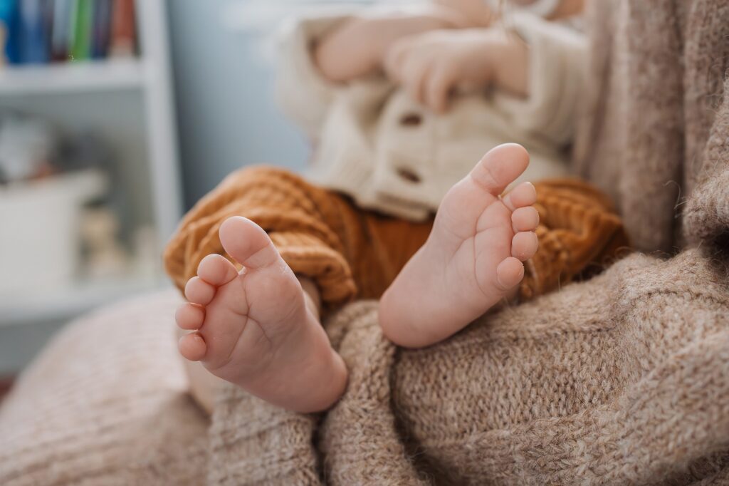 Bare baby feet peeking out from a cozy knit blanket.