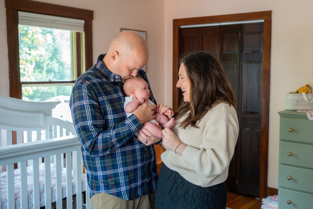 A couple lovingly looks at their baby in a nursery.