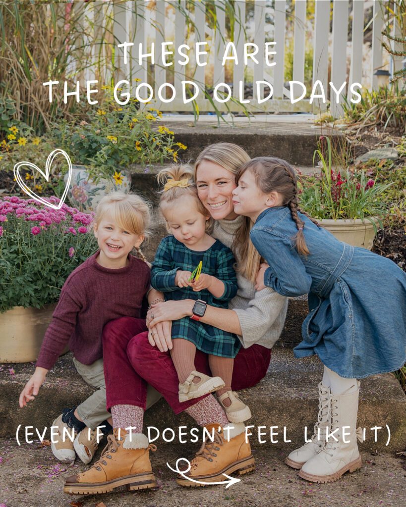 A woman sits on steps hugging three young girls, surrounded by flowers, with text overlay that reads “These are the good old days (even if it doesn't feel like it).”.