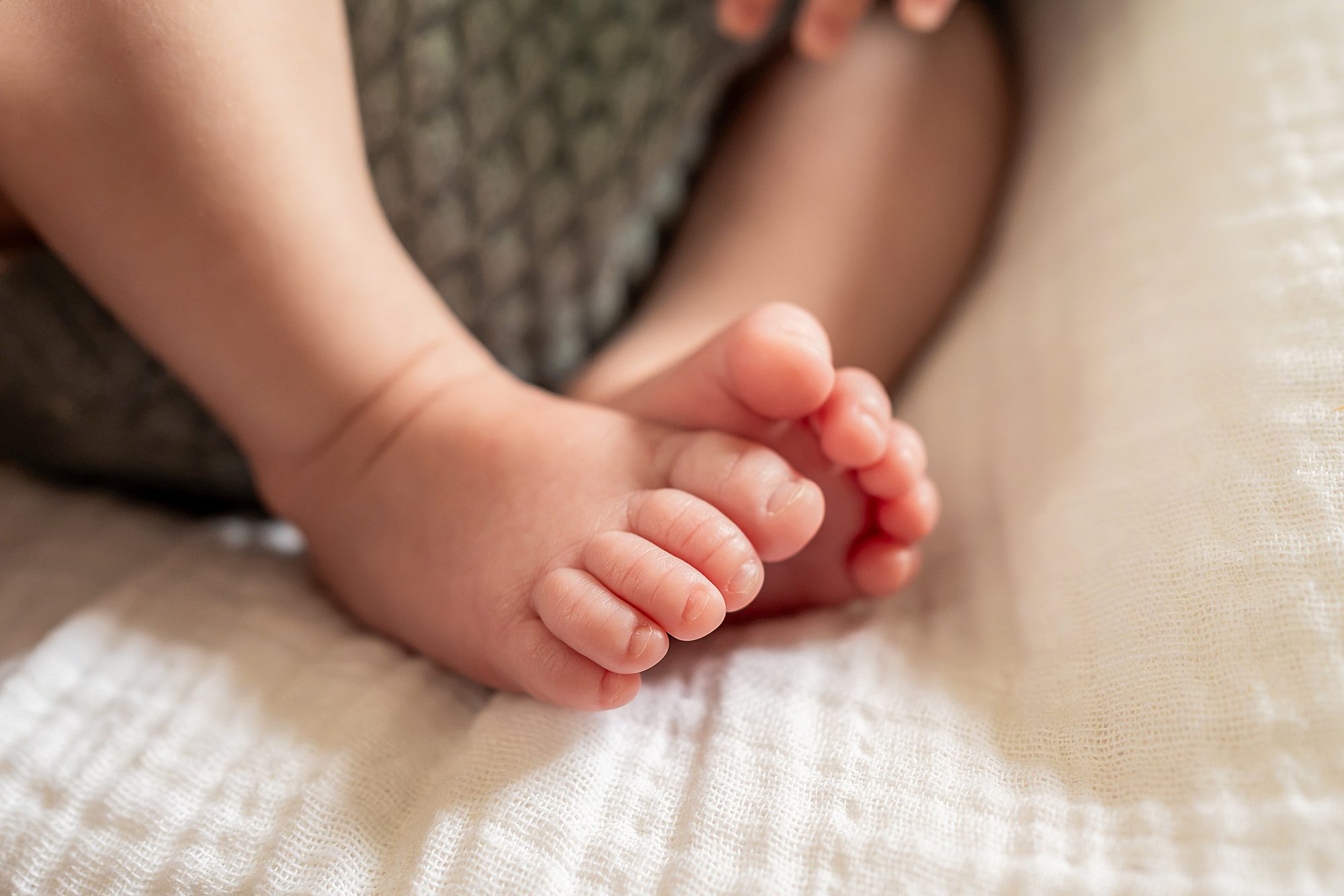 Close-up of a baby’s bare feet resting on a white textured blanket.